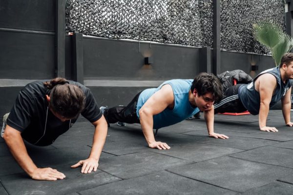 Men performing push-ups during a group workout session in Mexico City gym.