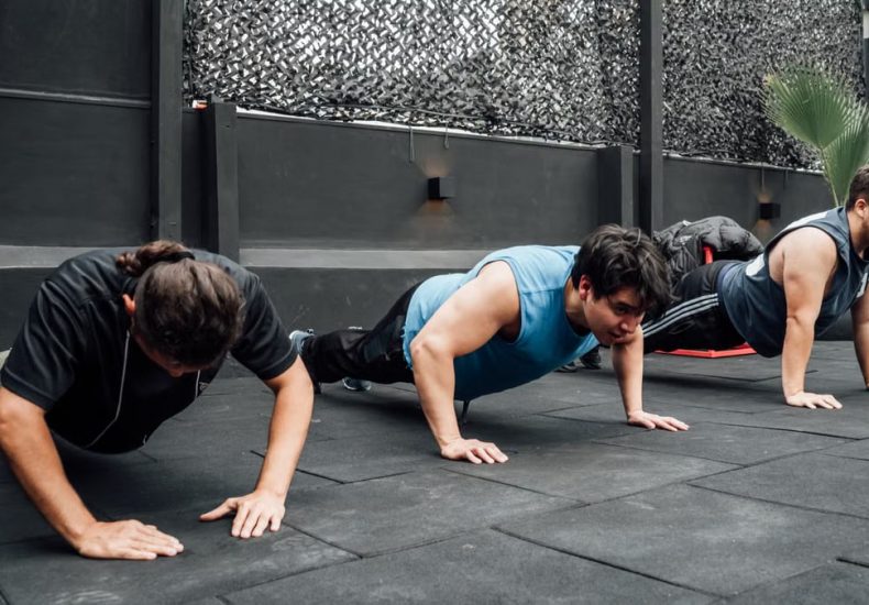 Men performing push-ups during a group workout session in Mexico City gym.